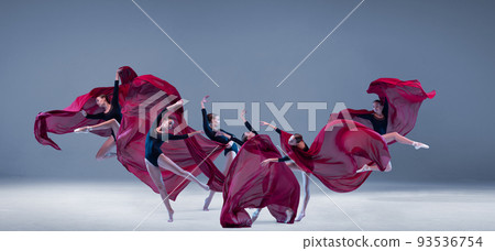 Portrait of young ballerina dancing with deep red clored fabric isolated over blue grey studio background. Flower bloom. Art style 93536754
