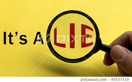 It's a lie text on yellow cover with hand holding magnifying glass. Scamming and fraud concept 93537519