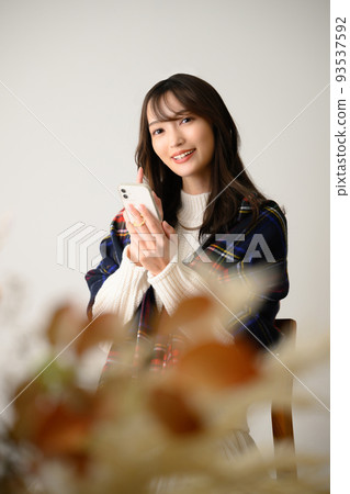 A woman touching a smartphone Winter image vertical 93537592
