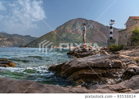 Man Tourists Standing on Cliff near Lighthouse in Montenegro Man Tourists Standing on Cliff near Lighthouse in Montenegro 93538814