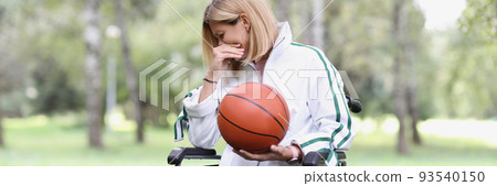 Sad woman in wheelchair is holding basketball 93540150
