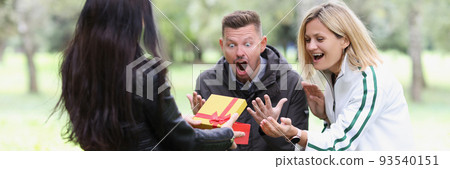 Woman opens gift box and couple looks on happily 93540151