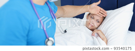 Doctor keeps hand on forehead of sick woman on bed 93540175