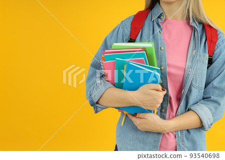 Student girl with notebooks on yellow background Student girl with notebooks on yellow background 93540698