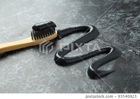 Wooden toothbrush with black toothpaste, close up 93540923