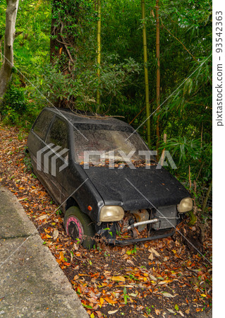 A light car abandoned along a road in the mountains 93542363