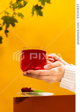 Cup of delicious berry tea with raspberry, mint and cinnamon stick isolated over orange background. Healthy hot drink Cup of delicious berry tea with raspberry, mint and cinnamon stick isolated over orange background. Healthy hot drink 93543637
