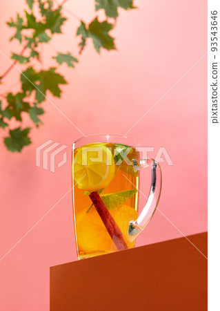 Glass of delicious aromatic citrus tea with lemons mint and cinnamon stick isolated over pink background Glass of delicious aromatic citrus tea with lemons mint and cinnamon stick isolated over pink background 93543646