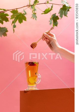 Glass of delicious aromatic herbal tea with citrus, lemons and oranges, honey and anise isolated over pink background 93543650