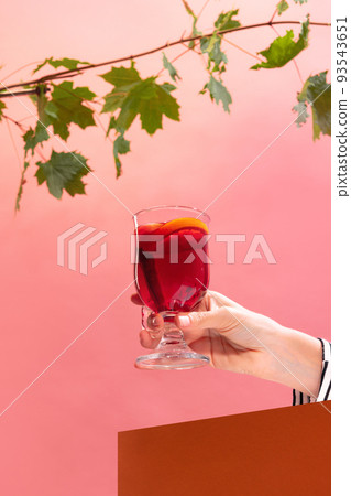 Glass with delicious aromatic cocktail, mulled wine with orange slice and cinnamon stick isolated over pink background Glass with delicious aromatic cocktail, mulled wine with orange slice and cinnamon stick isolated over pink background 93543651
