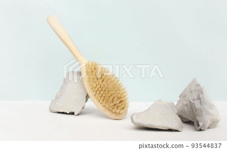 Natural wooden body brush balancing on rocks, on light background. Massage, relax, spa. Zero waste product. Natural wooden body brush balancing on rocks, on light background. Massage, relax, spa. Zero waste product. 93544837
