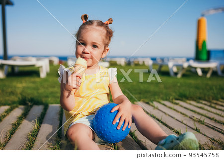 Adorable toddler girl eating ice cream outdoors Adorable toddler girl eating ice cream outdoors 93545758