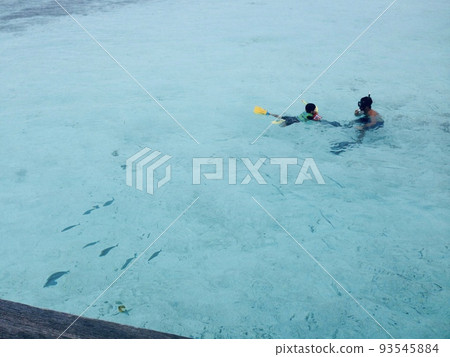 父親和兒子和魚一起游泳。在馬爾代夫海域。 父親和兒子和魚一起游泳。在馬爾代夫海域。 93545884