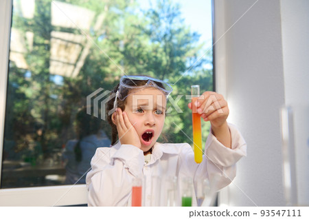 Smart Caucasian schoolgirl watching fascinating wonderful chemical reaction, between multi-colored chemicals and reagents, taking place in a test tube that she holds in her hands at a chemistry lesson Smart Caucasian schoolgirl watching fascinating wonderful chemical reaction, between multi-colored chemicals and reagents, taking place in a test tube that she holds in her hands at a chemistry lesson 93547111