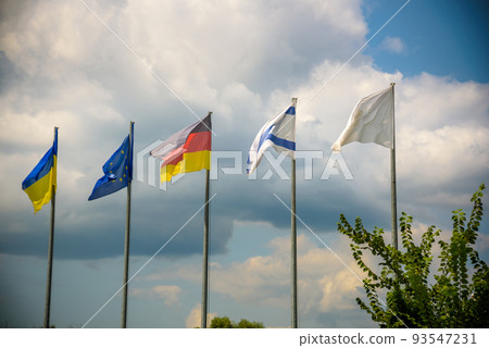 The flag of the European Union and flags of Ukraine, Israel, Germany flutter in the wind in different directions against the blue sky. Bottom side view 93547231