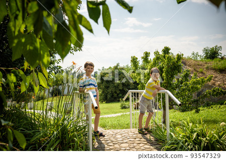 Summer adventure friendship childhood concept. Two children boy thinking secret plans or ideas on wooden bridge by stream in summer Summer adventure friendship childhood concept. Two children boy thinking secret plans or ideas on wooden bridge by stream in summer 93547329