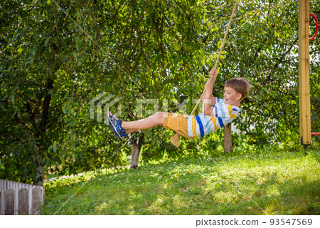 Two adorable happy little boys is having fun on a rope swing which he has found while having rest outside city. Active leisure time with children 93547569
