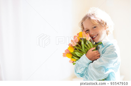 Child with flower bouquet. Mother day greeting. 93547910