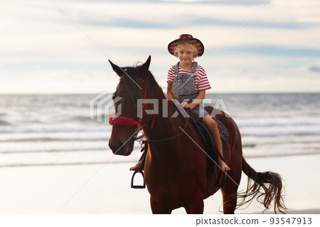Kids riding horse on beach. Children ride horses. 93547913