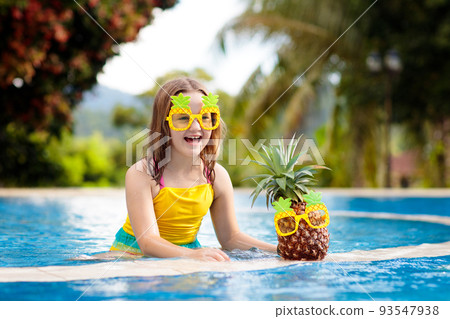 Child with pineapple in swimming pool. Kids swim. 93547938