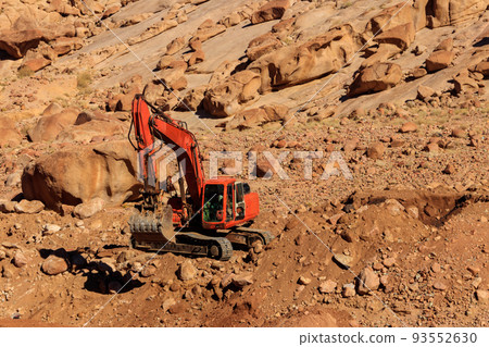 Orange excavator working at construction site in desert in Sinai peninsula, Egypt Orange excavator working at construction site in desert in Sinai peninsula, Egypt 93552630