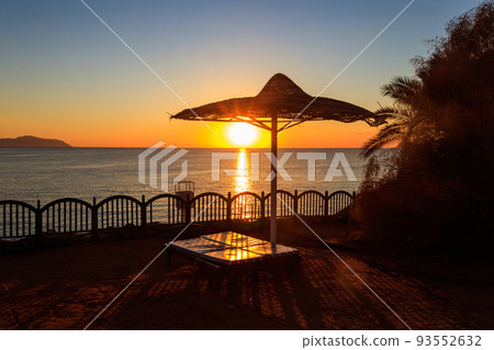 Sun umbrellas and chaise lounges on tropical beach at sunrise. Concept of rest, relaxation, holidays, resort 93552632