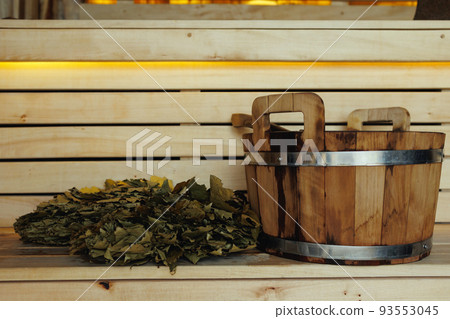 Bucket and broom for a bath on wooden planks of a bench in a sauna Bucket and broom for a bath on wooden planks of a bench in a sauna 93553045