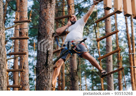 A man overcomes an obstacle in a rope town. A man in a forest rope park 93553268
