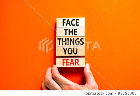 Face the things you fear symbol. Concept words Face the things you fear on wooden blocks on a beautiful orange background. Businessman hand. Business and face the things you fear concept. Copy space. 93553305