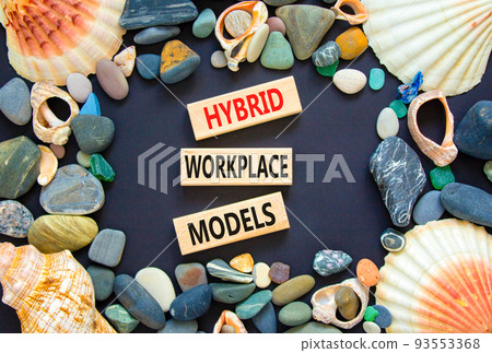 Hybrid workplace models symbol. Concept words Hybrid workplace models on wooden blocks. Beautiful black background. Sea stones and sea shells. Business hybrid workplace models concept. Copy space 93553368