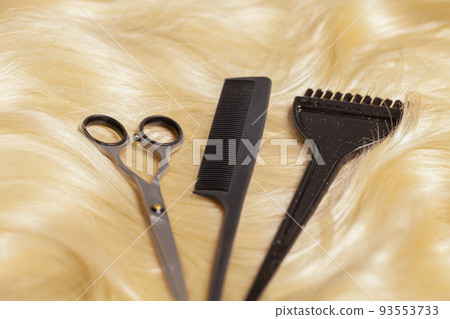 Professional scissors, comb and hairdressing brush on blonde hair Professional scissors, comb and hairdressing brush on blonde hair 93553733