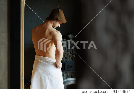 Handsome man puts on a towel after bath procedures in a spa resort 93554635