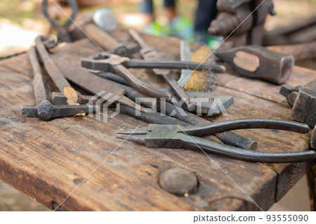 Blacksmith tools and instruments at outdoor forge, workshop - close up Blacksmith tools and instruments at outdoor forge, workshop - close up 93555090