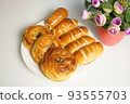 freshly baked assorted rolls with a stuffing in a white plate on the table. 93555703