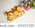 freshly baked assorted rolls with a stuffing in a white plate on the table. 93555705