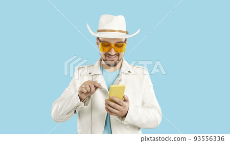 Smiling man in summer wear using modern cellphone Smiling man in summer wear using modern cellphone 93556336