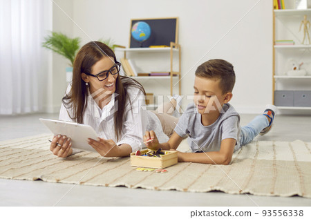 Happy boy having fun while learning letters with a professional speech therapist 93556338