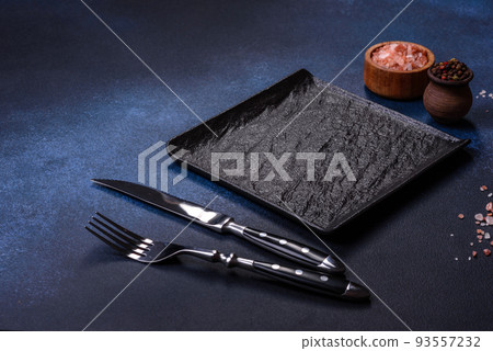Empty square black plate on dark moody background with copy space Empty square black plate on dark moody background with copy space 93557232