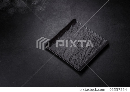 Empty square black plate on dark moody background with copy space 93557234