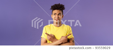 Close-up portrait of insecure, indecisive young hispanic man cant make up his mind, deciding between two variants, dont know what choose, need help with decision, pointing fingers left and right 93559029