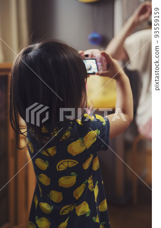 2 year old girl playing with toy camera 93559159