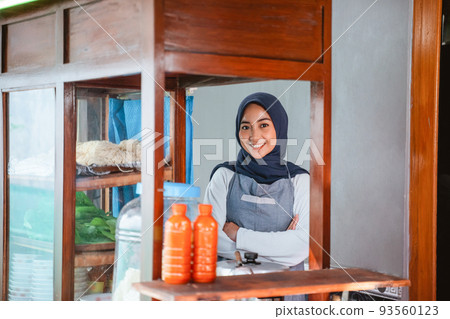 female seller in hijab wearing apron standing with crossed hands female seller in hijab wearing apron standing with crossed hands 93560123