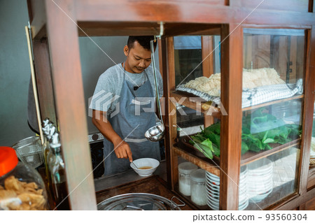 man seller in apron stir the spices in the bowl 93560304