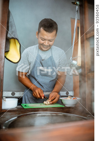 the seller slices the toppings while preparing the dish 93560458