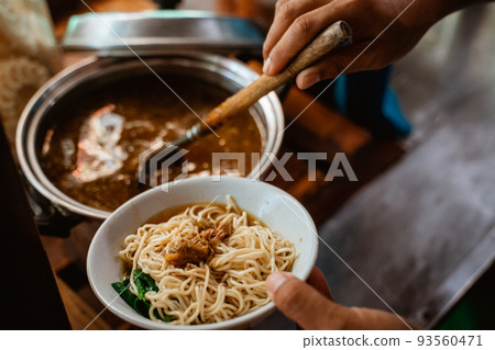 close up of seller's hand prepare noodles in a bowl 93560471