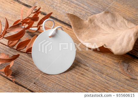 Round white tag mockup on a rustic wooden background with cotton string and boho decoration Round white tag mockup on a rustic wooden background with cotton string and boho decoration 93560615