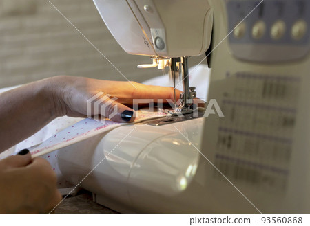 close-up of the seamstress's hands at the sewing machine hem fabric, clothing 93560868