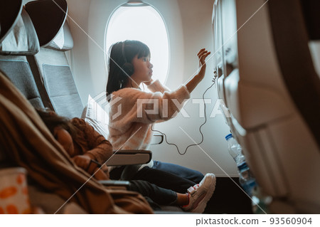 kid sitting on an airplane and watching movie 93560904