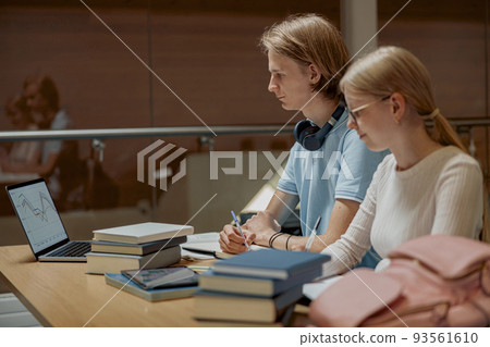 Students sit in the library and take notes while preparing for the exam 93561610