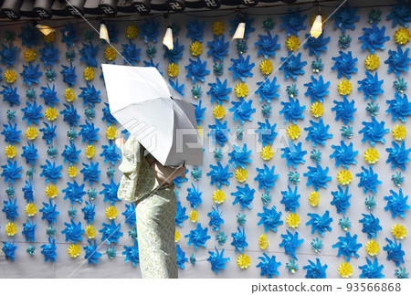 一位身穿日本和服並打著遮陽傘的女性的背影，她在風車的 Instagrammable 牆前擺姿勢。它曾經被稱為上鏡 93566868
